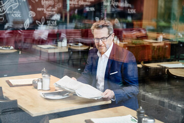 Mature businessman in cafe reading newspaper