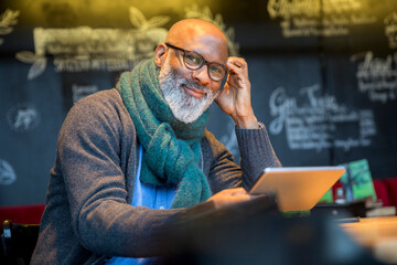 Portrait of smiling man with tablet in a coffee shop