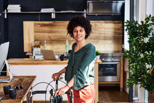 Portrait of smiling young woman with bicycle in modern office