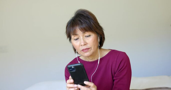 Good looking mature stylish woman wearing ear buds relaxing listening to peaceful music