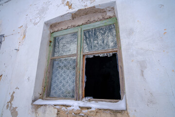 a broken window of an abandoned house. a house without owners