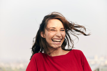 Cheerful woman standing against clear sky