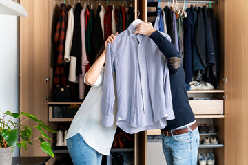 Copule clearing out her wardrobe hiding behind a shirt