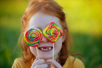 Happy girl covering her eyes with lollipops
