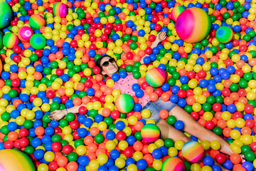 Portrait of happy woman lying among many colourful balls