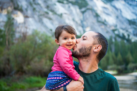 Portrait of happy baby girl kissed by her father, Yosemite National Park, California, USA