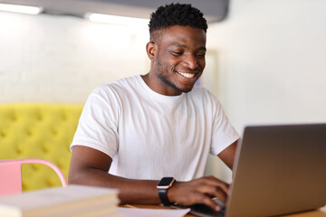 Obraz premium Happy young businessman using a laptop at a modern home office, exuding confidence and professionalism.