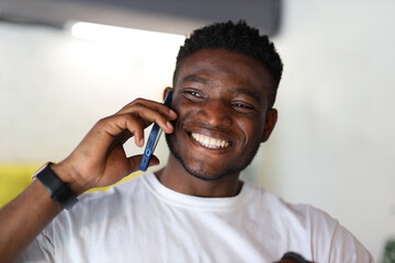 Happy young man holding a mobile phone, exuding cheerful confidence and modern lifestyle.