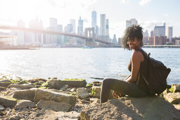 USA, New York City, Brooklyn, portrait of smiling woman sitting at the waterfront