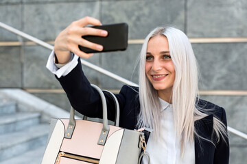 Smiling young woman ctaking a selfie on stairs in the city