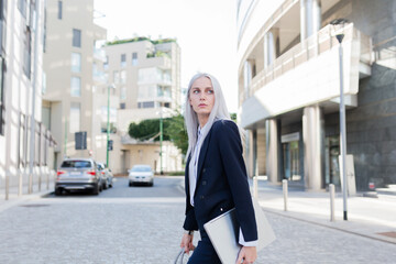 Young businesswoman with laptop on the go in the city