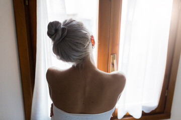 Rear view of young woman with hair bun looking out of window