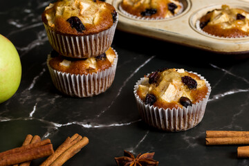 Homemade muffin with apples, raisins and cinnamon sticks. On a dark background