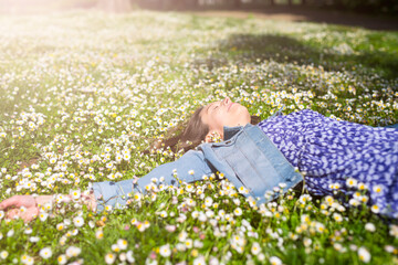 Relaxed young woman lying on flower meadow in a park