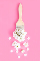 Creative flowers composition. Paintbrush with white flowers on the pink background.Top view.