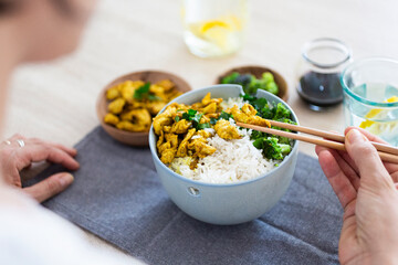 Curry chicken, broccoli and rice, woman with chopsticks