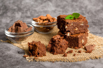 Chocolate brownie cake. Pieces of homemade chocolate brownie with mint leaves and nuts. Photo for advertising confectionery products. Close-up