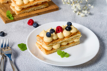 Millefeuille cake. Dessert millefeuille of puff pastry layered with custard cream, raspberries, blueberries. Photo for advertising confectionery products. Close-up
