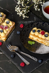Millefeuille cake. Dessert millefeuille of puff pastry layered with custard cream, raspberries, blueberries. Photo for advertising confectionery products. Close-up