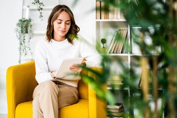 Businesswoman using digital tablet while sitting on sofa at office