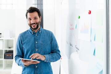 Portrait of smiling business man standing at whiteboard in office