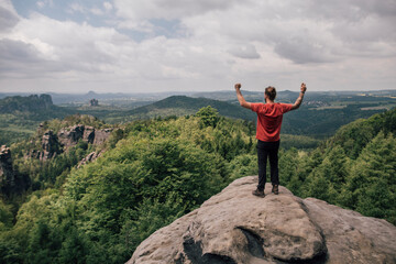 Germany, Saxony, Elbe Sandstone Mountains, man on a hiking trip standing on rock cheering