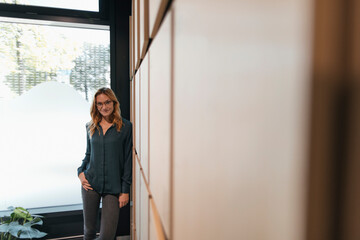 Portrait of smiling businesswoman standing at a wall
