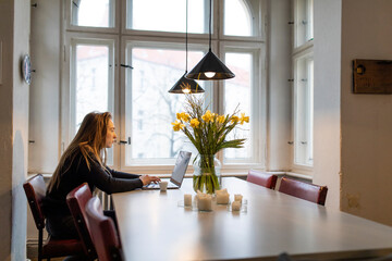 Young woman using laptop on table at home