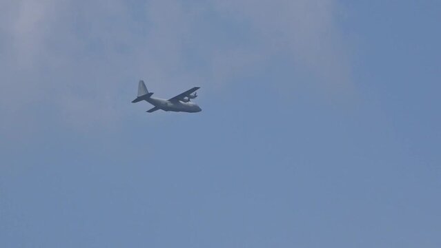 Military Transport aircraft seen flying in the distance through clouds on evacuation air bridge mission