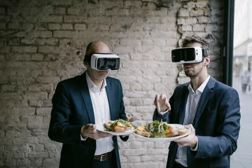 Schilderijen op glas Senior and mid-adult businessman wearing VR glasses holding plate with a meal © tunedin