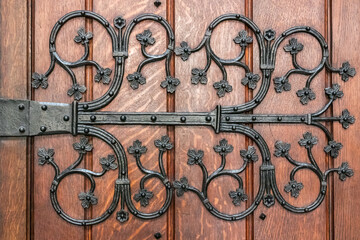Richly ornamented, iron cast hinge of an old wooden door.