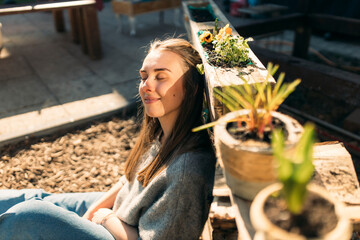 Young woman enjoying the sunshine in garden - obrazy, fototapety, plakaty