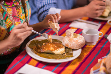 Person eating a tamale, accompanied by bread from the region.