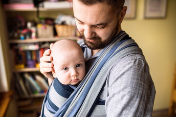 Father with baby son in sling at home