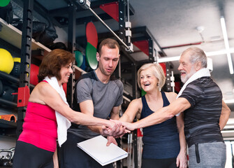 Group of fit seniors with personal trainer in gym