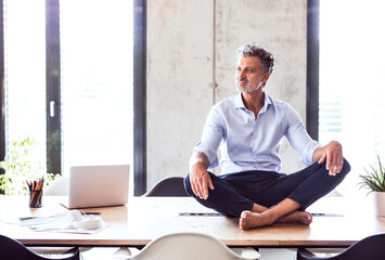Mature businessman sitting barefoot on desk in office