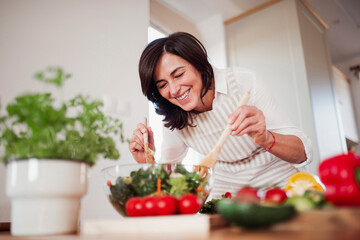 Mature woman preparing salad in her kitchen