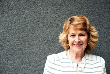 Portrait of smiling senior businesswoman against grey wall
