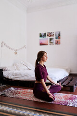 Young brunette woman practising yoga in student dorm