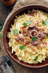 Traditional swabian cheese spaetzle, egg noodles with cheese, cream, roasted onions