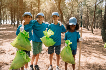 Group portrait of volunteering children collecting garbage in a park