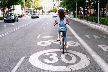 Mature woman riding on bicycle lane in city
