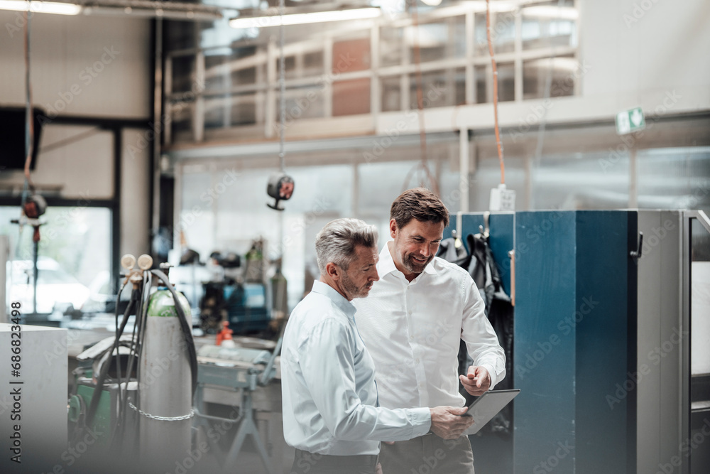 Canvas Prints businessman discussing with male colleague over digital tablet in industry