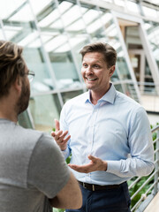 Businessman talking to colleague in atrium of office building