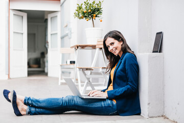 Smiling businesswoman using laptop on the floor