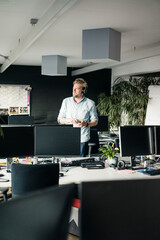 Businessman with cell phone and headphones in office