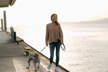 Germany, Hamburg, woman walking with dog on pier at the Elbe shore