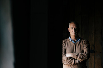 Portrait of serious senior businessman in front of wooden wall
