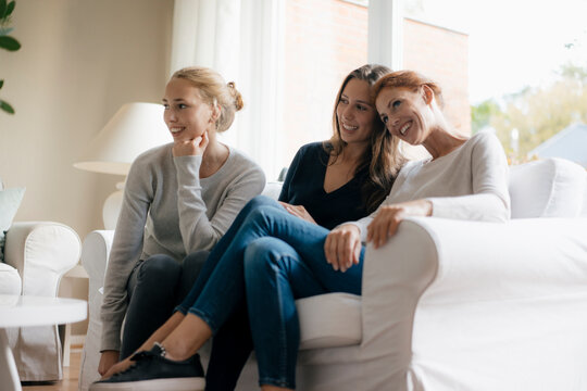 Happy Mother With Two Teenage Girls On Couch At Home