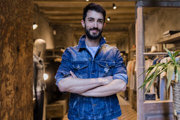Portrait of smiling man wearing denim jacket in menswear shop